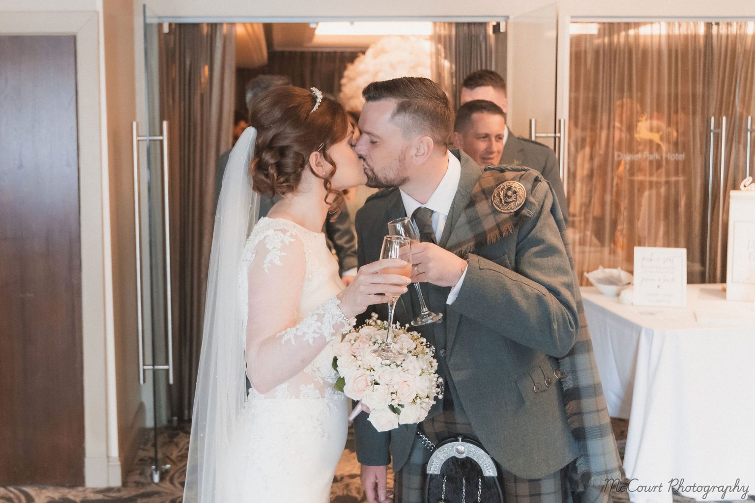 Sarah and Patrick manson celebrating just getting married with a kiss in the dalziel park hotel.